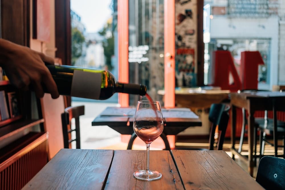 wine glass on table is filled with red wine - restaurant with open door and empty tables