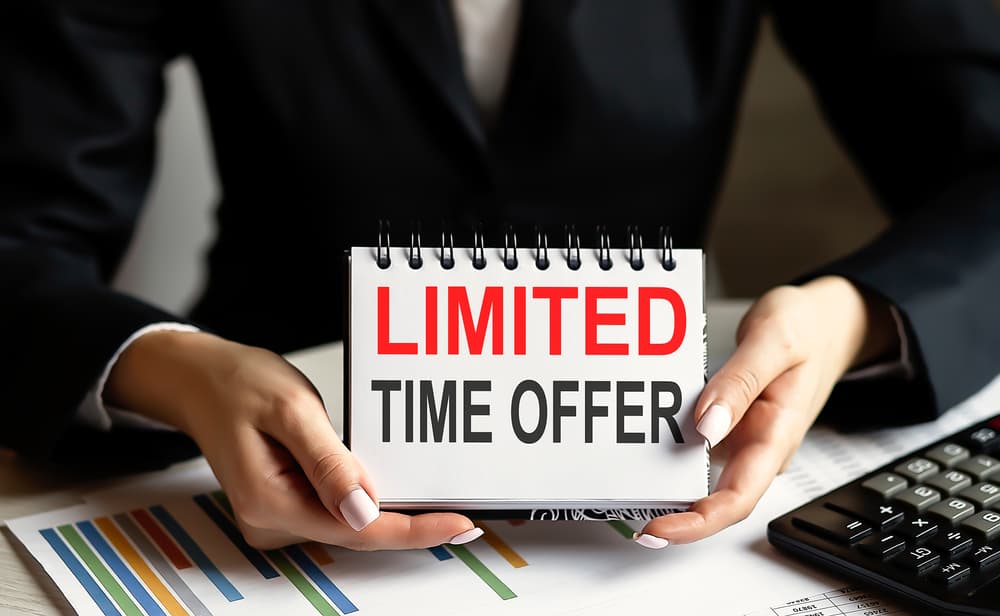 A businesswoman holding a card with the text "LIMITED TIME OFFER" against the backdrop of a chart.