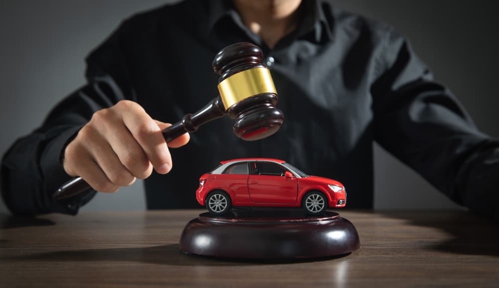 A judge holding a gavel and a red toy car.






