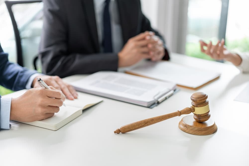 A law consultation concept: a businessman in a black suit discussing legal matters with a law officer in a deep blue suit and his assistant. 