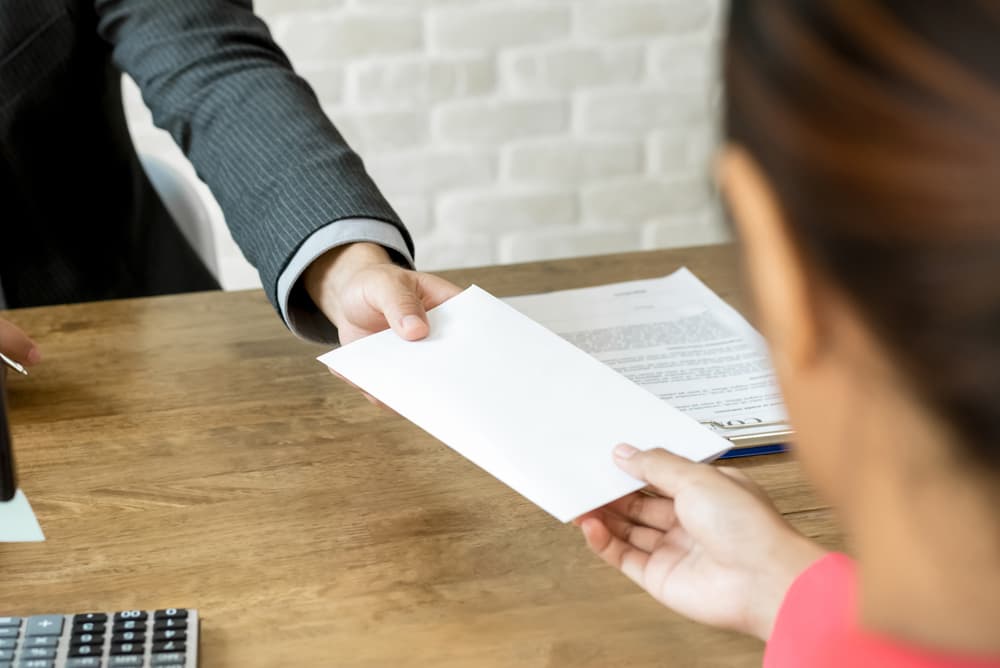 A man is offering a envelope to a woman