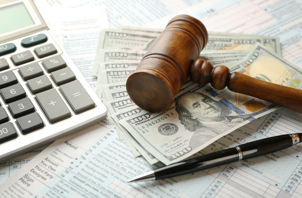 A judge's gavel and dollar banknotes placed on an income tax form background.