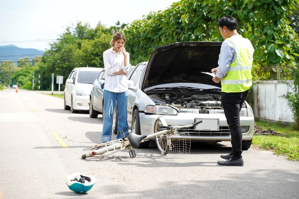 An insurance agent is asking a female driver about a bicycle crash on road.